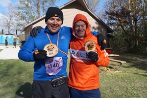 Two male finishers holding branded finishers wood plaque.